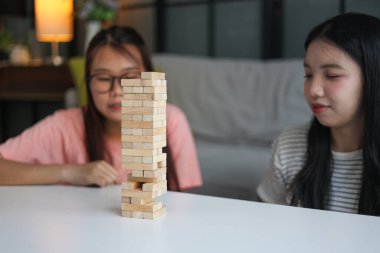 İki genç bayan arkadaş evlerinde tahta kule blokları masa oyunu oynuyorlar..