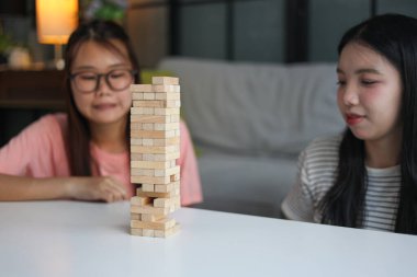 İki genç bayan arkadaş evlerinde tahta kule blokları masa oyunu oynuyorlar..