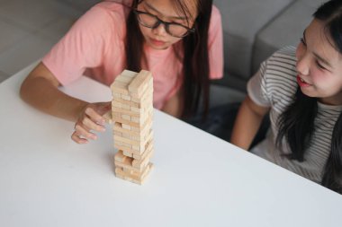 İki genç bayan arkadaş evlerinde tahta kule blokları masa oyunu oynuyorlar..