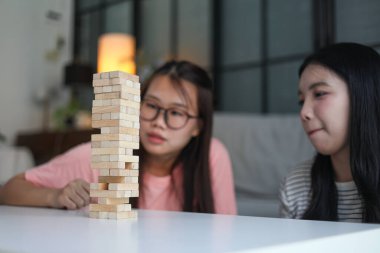 İki genç bayan arkadaş evlerinde tahta kule blokları masa oyunu oynuyorlar..