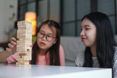 İki genç bayan arkadaş evlerinde tahta kule blokları masa oyunu oynuyorlar..