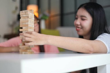 İki genç bayan arkadaş evlerinde tahta kule blokları masa oyunu oynuyorlar..