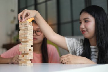 İki genç bayan arkadaş evlerinde tahta kule blokları masa oyunu oynuyorlar..