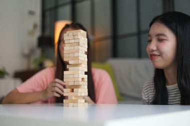 İki genç bayan arkadaş evlerinde tahta kule blokları masa oyunu oynuyorlar..
