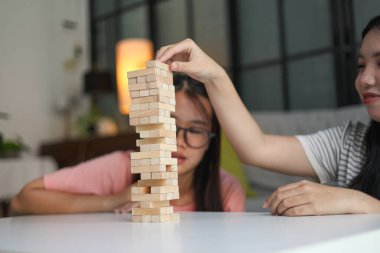 İki genç bayan arkadaş evlerinde tahta kule blokları masa oyunu oynuyorlar..