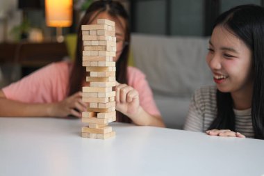 İki genç bayan arkadaş evlerinde tahta kule blokları masa oyunu oynuyorlar..