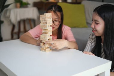İki genç bayan arkadaş evlerinde tahta kule blokları masa oyunu oynuyorlar..