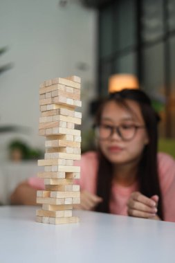 Genç bayan evde tahta kule blokları oyunu oynuyor..
