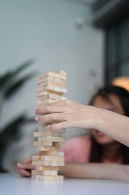 İki genç bayan arkadaş evlerinde tahta kule blokları masa oyunu oynuyorlar..