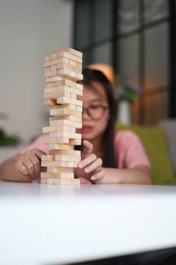 Genç bayan evde tahta kule blokları oyunu oynuyor..