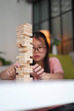 Genç bayan evde tahta kule blokları oyunu oynuyor..