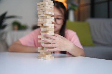 Genç bayan evde tahta kule blokları oyunu oynuyor..