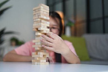 Genç bayan evde tahta kule blokları oyunu oynuyor..