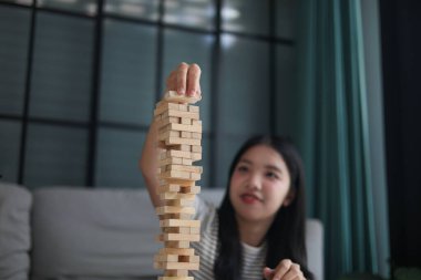 Genç bayan evde tahta kule blokları oyunu oynuyor..