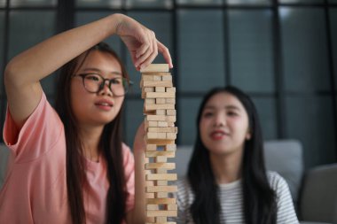 İki genç bayan arkadaş evlerinde tahta kule blokları masa oyunu oynuyorlar..