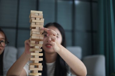 İki genç bayan arkadaş evlerinde tahta kule blokları masa oyunu oynuyorlar..