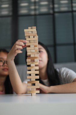 İki genç bayan arkadaş evlerinde tahta kule blokları masa oyunu oynuyorlar..