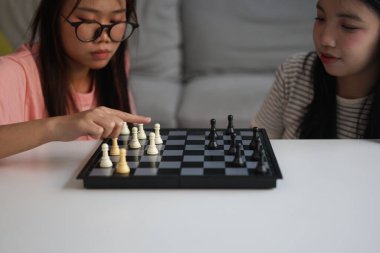 Evde birlikte satranç oynayan iki genç bayan arkadaş..