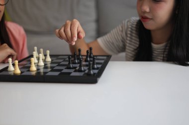 Evde birlikte satranç oynayan iki genç bayan arkadaş..