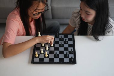 Evde birlikte satranç oynayan iki genç bayan arkadaş..