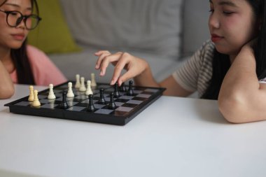 Evde birlikte satranç oynayan iki genç bayan arkadaş..