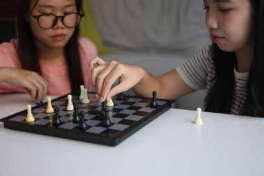 Evde birlikte satranç oynayan iki genç bayan arkadaş..