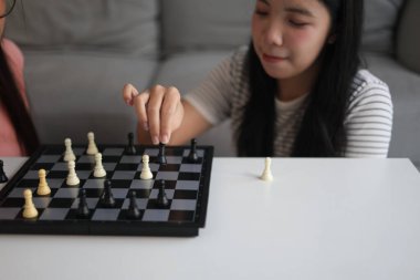 Evde birlikte satranç oynayan iki genç bayan arkadaş..