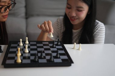 Evde birlikte satranç oynayan iki genç bayan arkadaş..