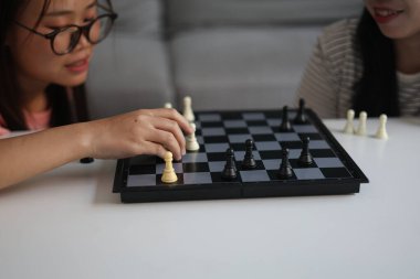 Evde birlikte satranç oynayan iki genç bayan arkadaş..