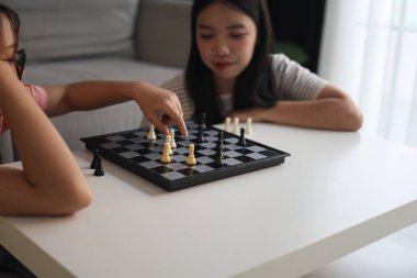 Evde birlikte satranç oynayan iki genç bayan arkadaş..