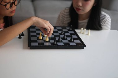 Evde birlikte satranç oynayan iki genç bayan arkadaş..