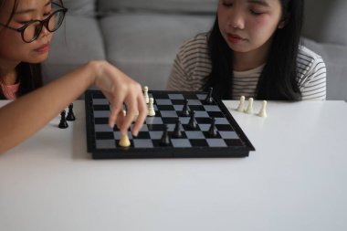 Evde birlikte satranç oynayan iki genç bayan arkadaş..