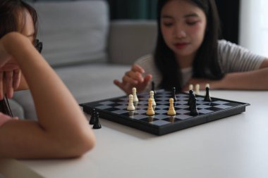 Evde birlikte satranç oynayan iki genç bayan arkadaş..