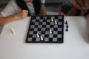 Evde birlikte satranç oynayan iki genç bayan arkadaş..