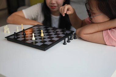 Evde birlikte satranç oynayan iki genç bayan arkadaş..