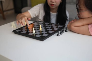 Evde birlikte satranç oynayan iki genç bayan arkadaş..