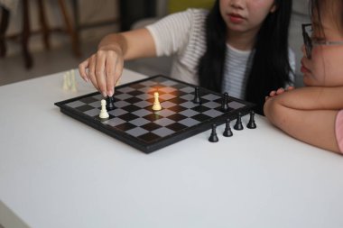 Evde birlikte satranç oynayan iki genç bayan arkadaş..