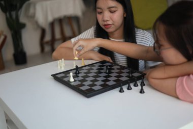 Evde birlikte satranç oynayan iki genç bayan arkadaş..