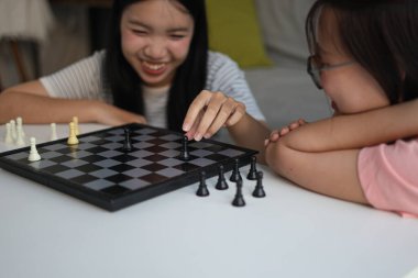 Evde birlikte satranç oynayan iki genç bayan arkadaş..