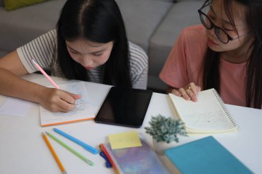 İki kadın öğrenci birlikte ödev yapıyor.