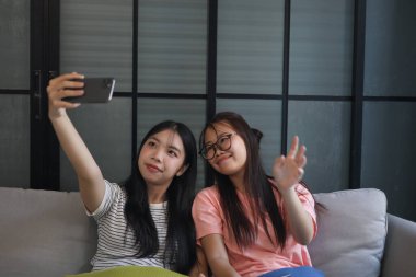 İki Asyalı bayan arkadaş içeride selfie çekiyor..