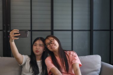 İki Asyalı bayan arkadaş içeride selfie çekiyor..