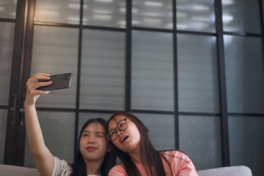 İki Asyalı bayan arkadaş içeride selfie çekiyor..