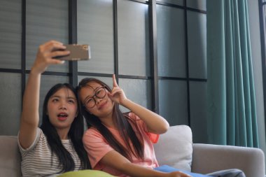İki Asyalı bayan arkadaş içeride selfie çekiyor..
