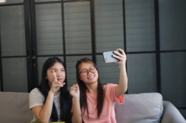 İki Asyalı bayan arkadaş içeride selfie çekiyor..