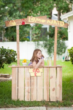 A bored young girl with no customers at her lemonade stand