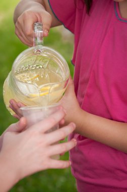 Young girl pouring lemonade from a glass pitcher