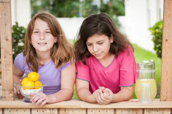 Two bored young girls selling lemonade — Zdjęcie stockowe