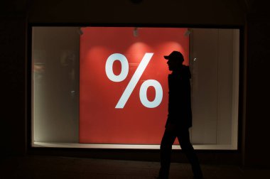 İsviçre 'nin Lugano şehrinden tanınmayan bir adamın geçtiği bir dükkan vitrininde yüzde kırmızı yanma işareti var..