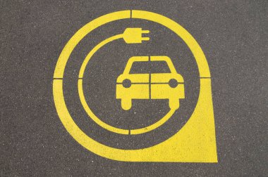 İsviçre 'nin Zug kentindeki siyah asfalt üzerinde sarı elektrikli araç şarj istasyonu sembolü